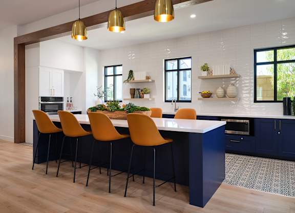 A kitchen with a long island and chairs.