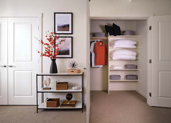 A white door is open to a hallway with a shelf and a vase on it.