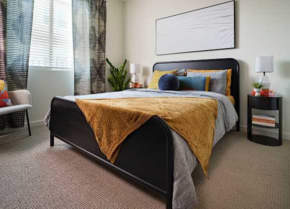 A bedroom with a large bed and a yellow blanket.