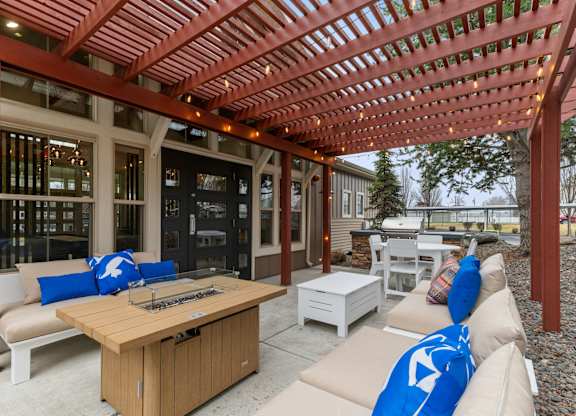 A wooden pergola with a table and chairs underneath it.