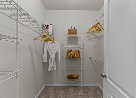 A white closet with a white robe hanging on a hanger.