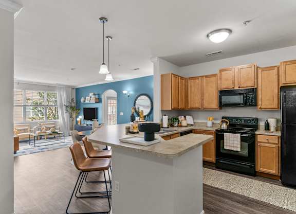 A kitchen with a black refrigerator and wooden cabinets.