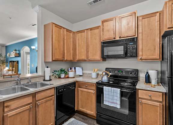 A kitchen with wooden cabinets and black appliances.