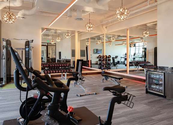A gym with a variety of exercise equipment including treadmills, stationary bikes, and weight machines.