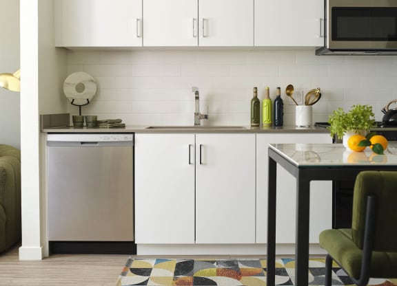 a small kitchen with white cabinets and a table
