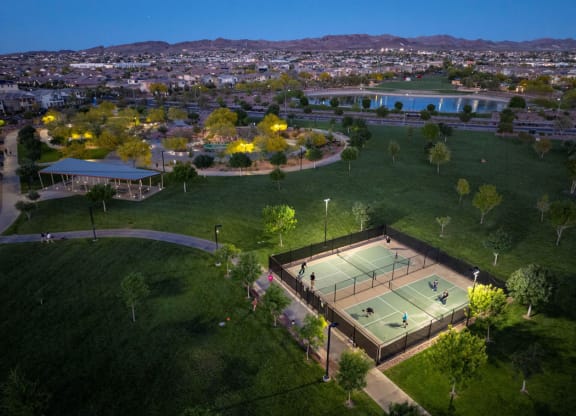 an aerial view of a tennis court with a city in the background