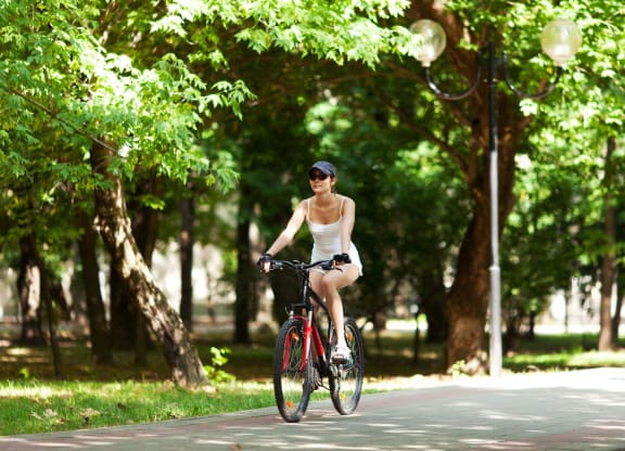 a woman riding a bike down a path in a park