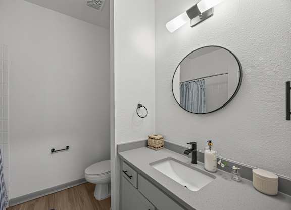 A bathroom with a toilet, sink, and mirror.