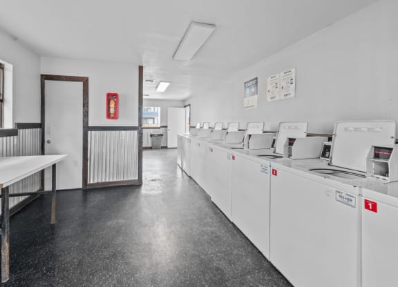 a laundry room with white walls and a black tiled floor