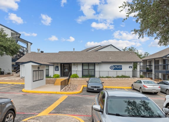 a white building with a gray roof and a parking lot in front of it