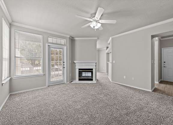 A spacious living room with a fireplace and a ceiling fan.