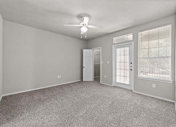 A spacious room with a carpeted floor and a ceiling fan.