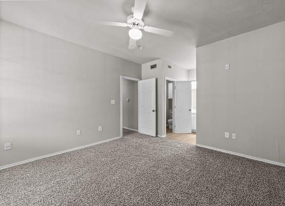 A room with a ceiling fan and carpeted floor.