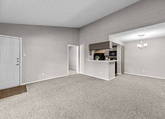 A spacious room with a carpeted floor and a white door.