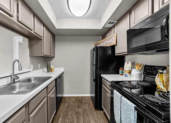 A kitchen with a black refrigerator and a white sink.