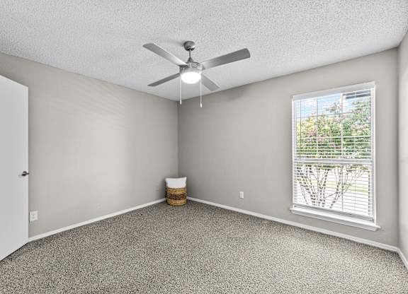 A room with a ceiling fan and a window with blinds.
