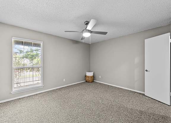 A room with a ceiling fan and a window with blinds.