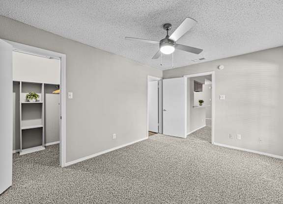 A room with a ceiling fan and carpeted floor.