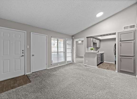 A spacious kitchen and living room with white appliances and a grey refrigerator.