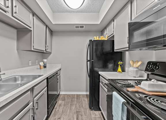 A kitchen with a black refrigerator and stove top oven.