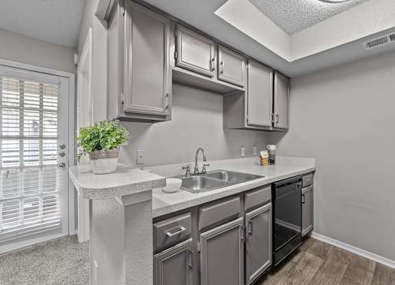 A kitchen with a sink, stove, and cabinets.