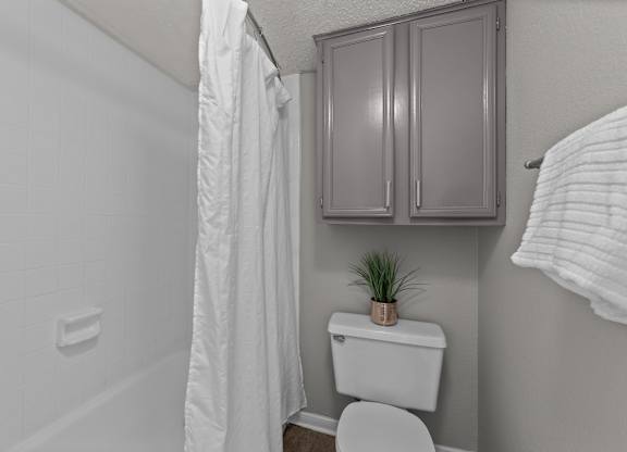 A white toilet sits in a bathroom next to a white shower curtain.