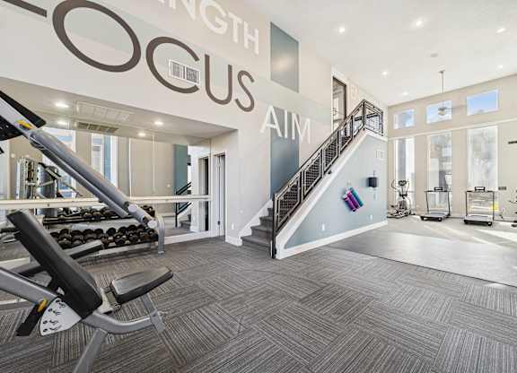 A gym with a staircase and a weight machine.