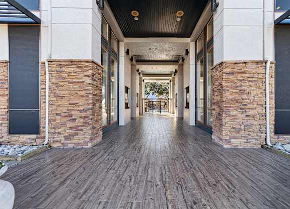 A long hallway with a wooden floor and stone pillars on either side.