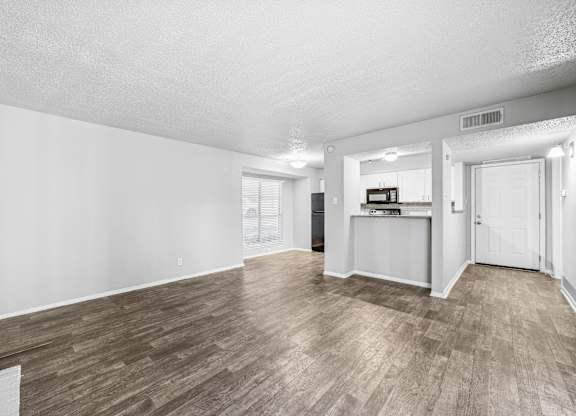 A spacious room with wooden flooring and white walls.