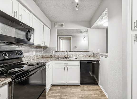 A kitchen with a black stove top oven and white cabinets.