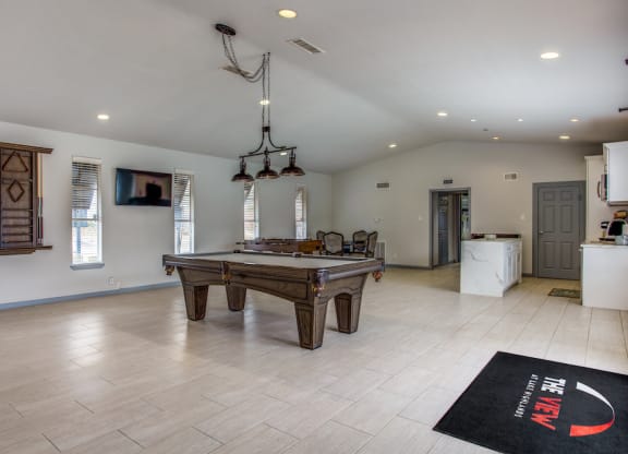 a large living room with a pool table and a kitchen