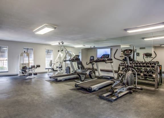 a spacious fitness room with cardio equipment and a flat screen tv