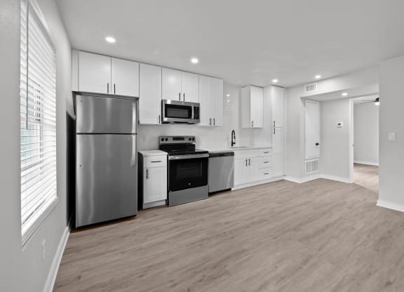 an empty kitchen with white cabinets and stainless steel appliances at Sunset Heights, Texas
