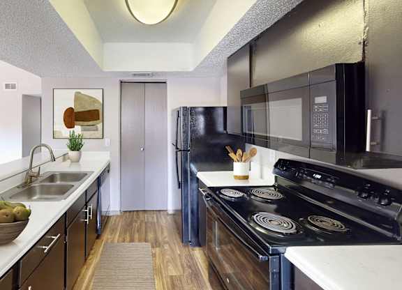 A modern kitchen with black appliances and a bowl of fruit on the counter.