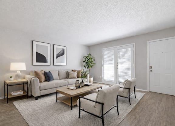 A living room with a grey couch, a coffee table, and two chairs.