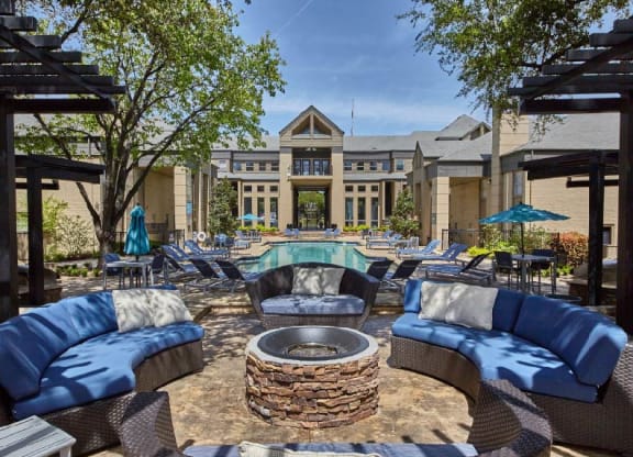 a patio with couches and a fire pit in front of a building