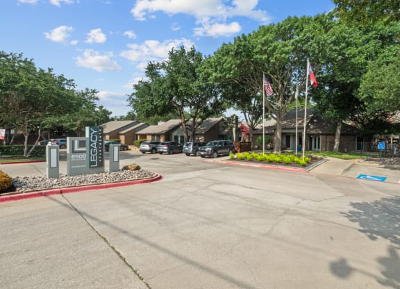 a parking lot with trees and buildings in the background