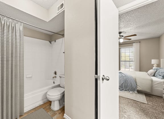 an open bathroom with a bed and a toilet in a bedroom