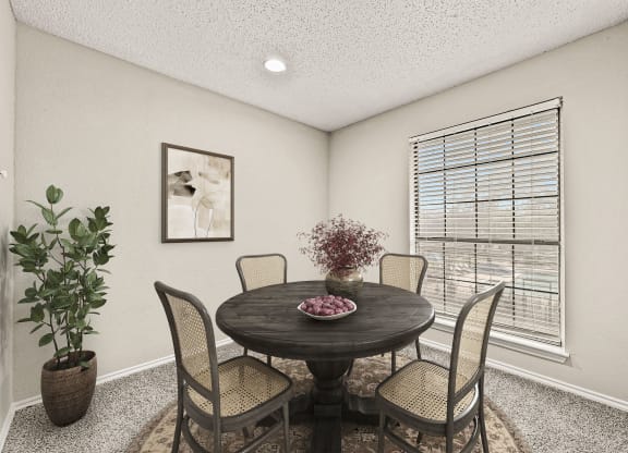a dining room with a table and chairs and a window at Legacy Apartments in Plano, TX