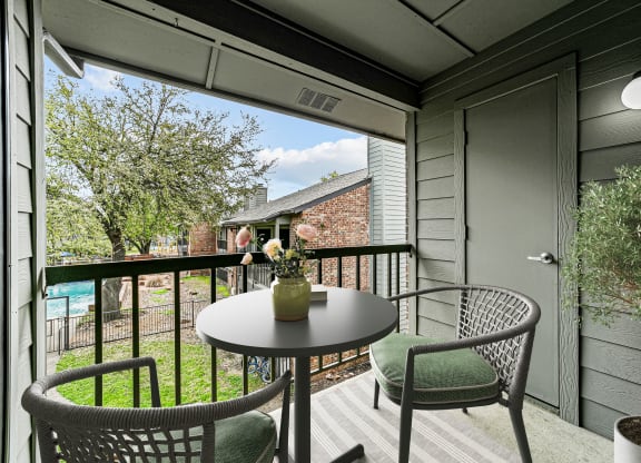 a patio with chairs and a table on a balcony at Legacy Apartments in Plano, TX
