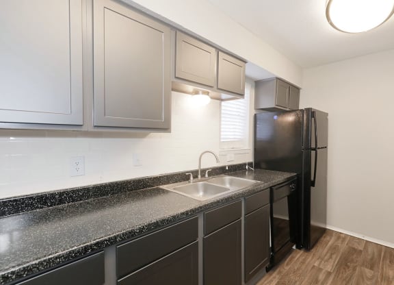 a kitchen with dark cabinets and a black refrigerator