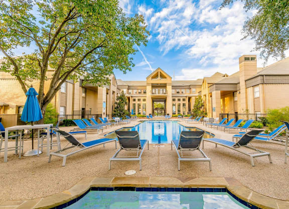 a swimming pool with chaise lounge chairs and a building in the background