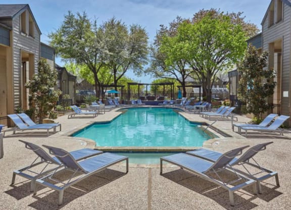 a swimming pool with chaise lounge chairs and trees in the background