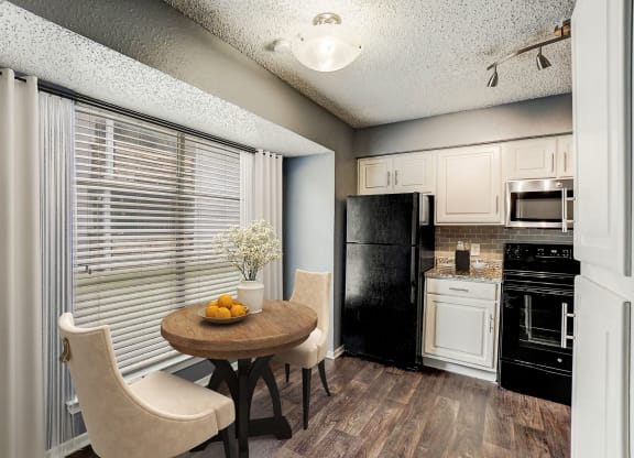 a kitchen with a table and chairs and a black refrigerator