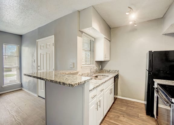 an empty kitchen with a granite counter top and white cabinets