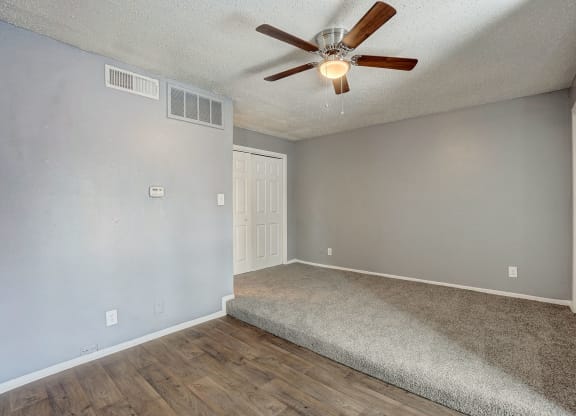 the spacious living room has a ceiling fan and a carpet
