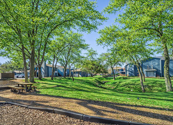A park with a picnic table and trees.