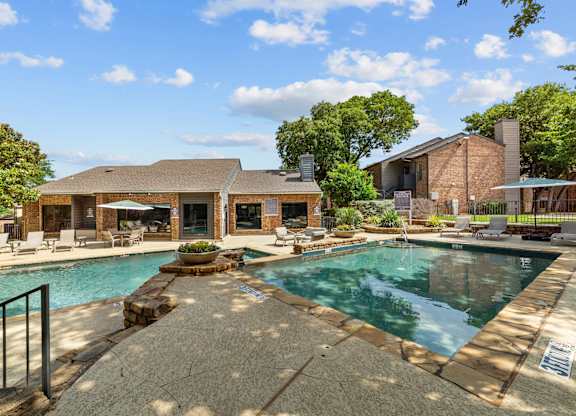 A pool surrounded by a patio and a house.