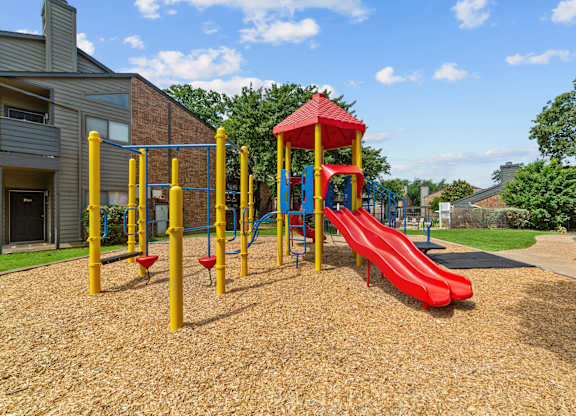 A playground with a red slide and yellow poles.