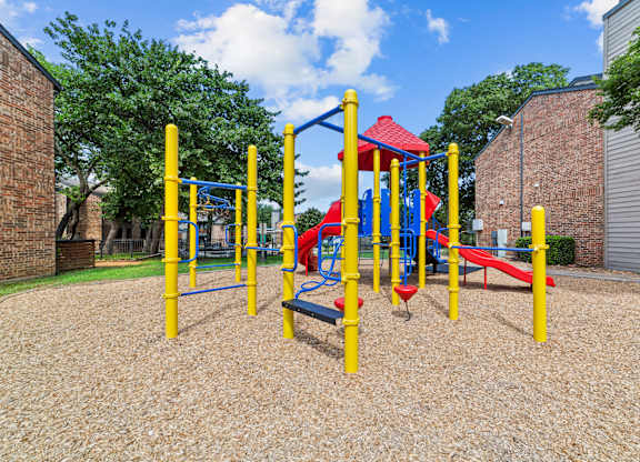A playground with a red slide and yellow poles.
